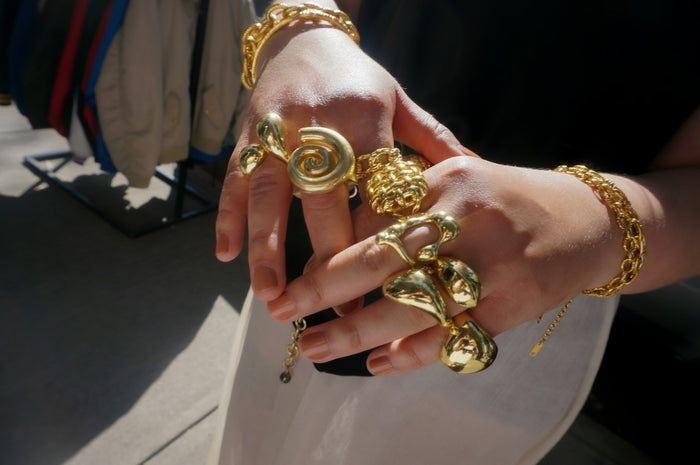 Hands adorned with chunky gold rings and bracelets