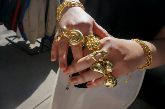 Hands adorned with chunky gold rings and bracelets